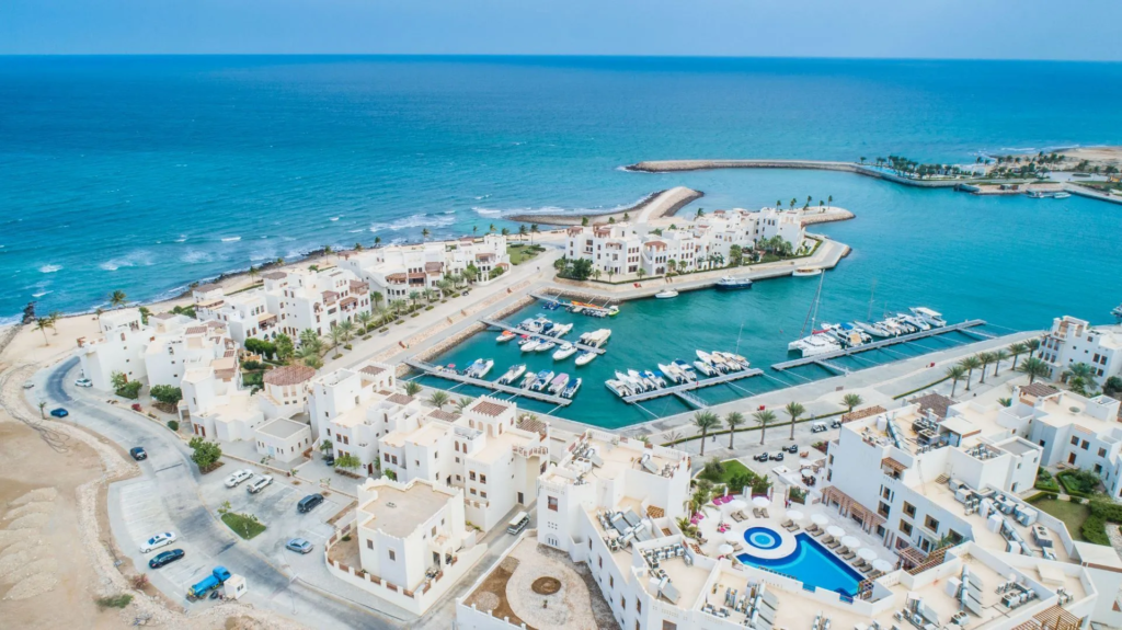 Aerial view of the Jebel Sifah resort community between the Hajar mountains and the Gulf of Oman