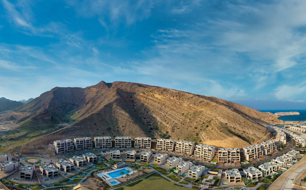 Aerial view of the Muscat Bay resort village, villas and hotel below the Hajar mountains